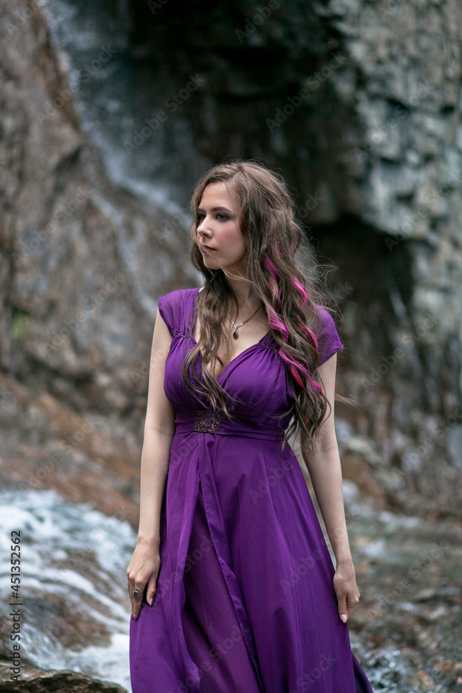 girl in a purple dress against the background of a mountain waterfall girl in a purple dress against the background of a mountain waterfall