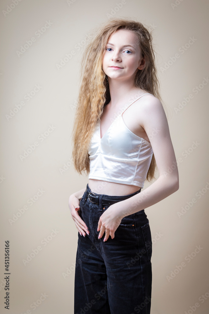 Caucasian Blond Girl Wearing White Bra with Jeans And Posing Over Beige Background. Caucasian Blond Girl Wearing White Bra with Jeans And Posing Over Beige Background.