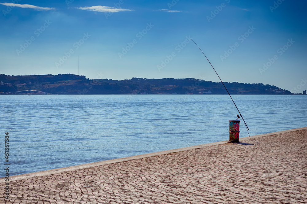 Fishing Rod On Colorful Metal Barrel Located on Pier of Lisbon in Portugal.