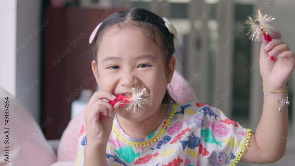 An Asian girl is happily playing with a flashing reflective toy. The girl is making a funny face with a wide smile showing her white teeth looking at the camera. An Asian girl is happily playing with a flashing reflective toy. The girl is making a funny face with a wide smile showing her white teeth looking at the camera.