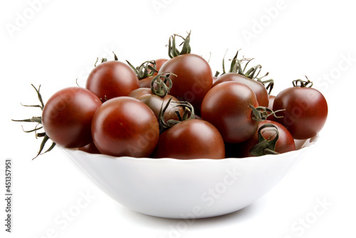 black cumato tomatoes in a white plate are isolated on a white background. photo