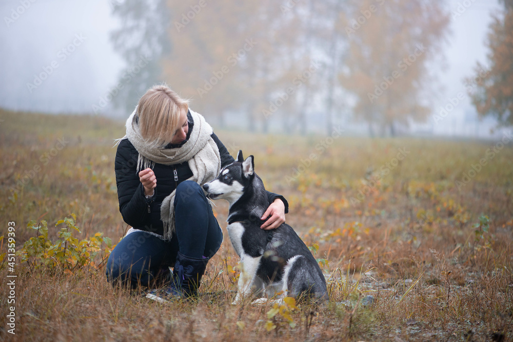 Young woman with beautiful siberian husky dog playing in city park during autumn Young woman with beautiful siberian husky dog playing in city park during autumn