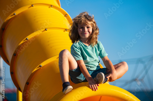 Joyful kid boy having fun on playground outdoors. Funny kids face.