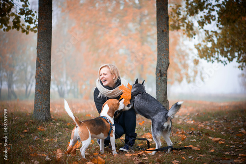 Photography Young woman pet owner with two dogs playing in autumn leaves
