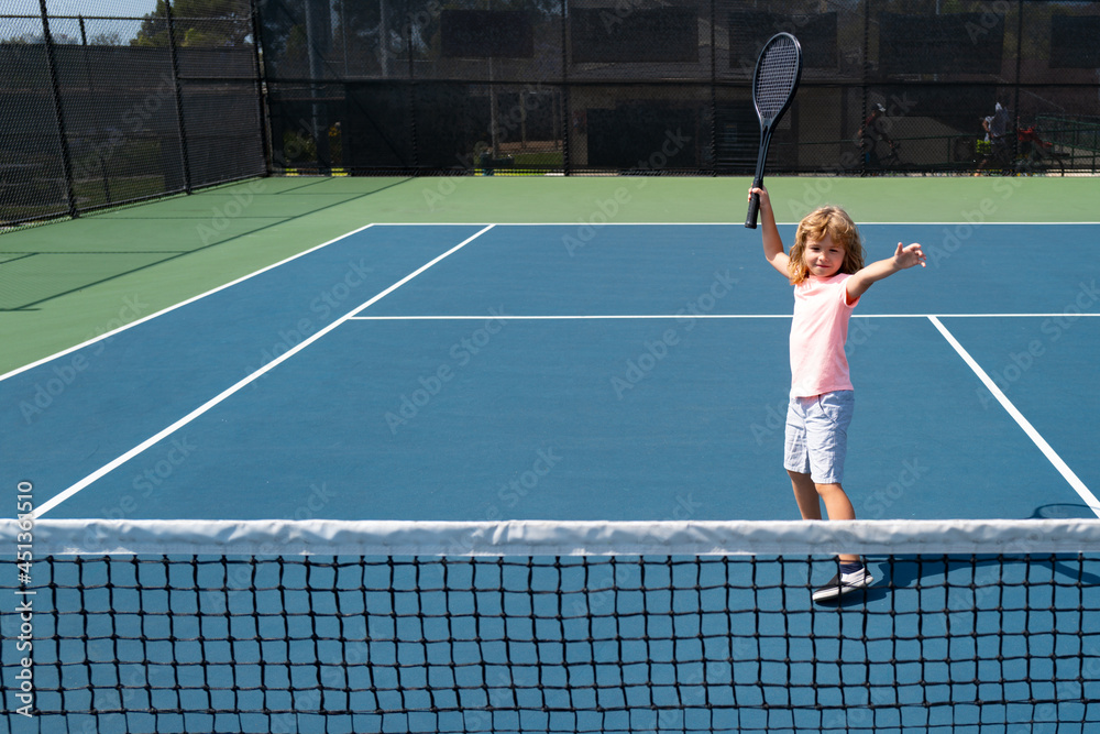 Child boy tennis player on tennis court.