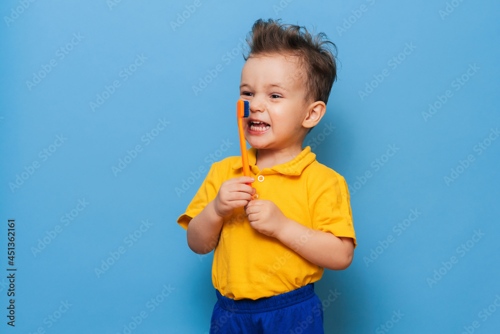 Happy child kid boy brushing teeth with toothbrush on blue background. Health care, dental hygiene. Mockup Happy child kid boy brushing teeth with toothbrush on blue background. Health care, dental hygiene. Mockup