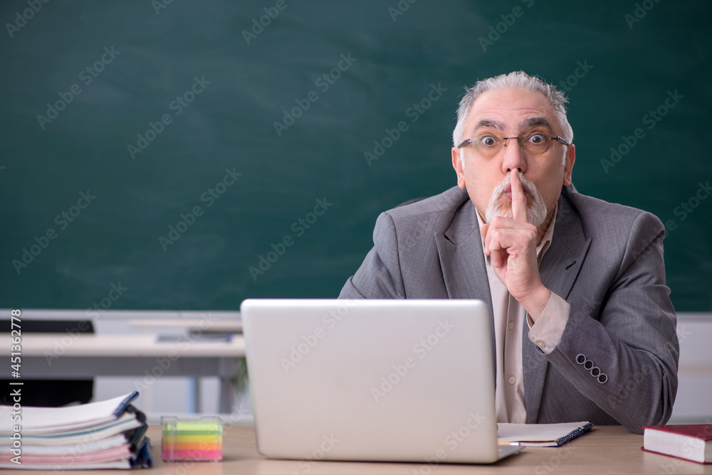 Old male teacher in front of blackboard Old male teacher in front of blackboard