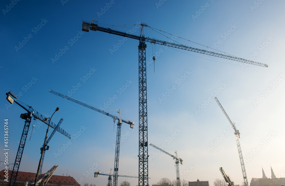 Construction cranes on a building site on a blue sky background
