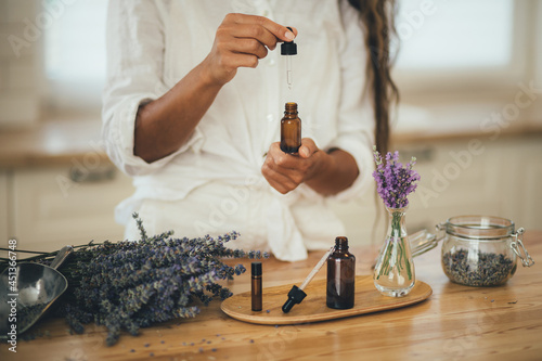 Young woman applying natural organic essential oil on hair and skin. Home spa and beauty rituals. photo