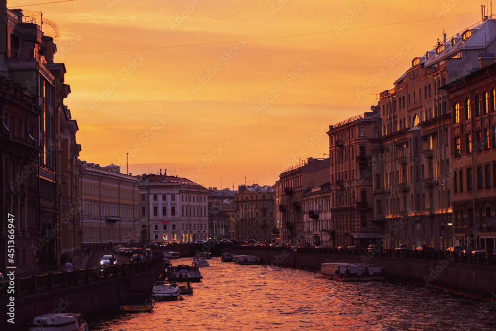 Orange sunset in St. Petersburg on the Moika River. The architecture of St. Petersburg in the sunset light on the river bank.