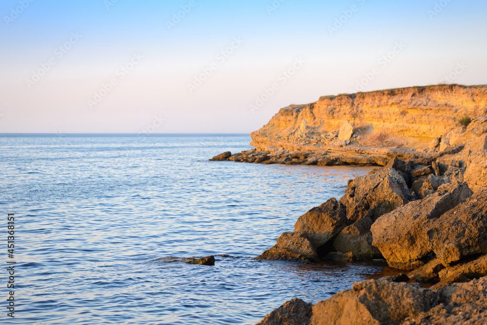 A rocky shore of a calm sea at sunset