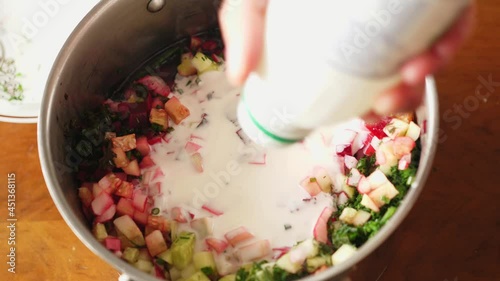 pouring buttermilk and curdled milk and kefir into vegetables chilled beet soup