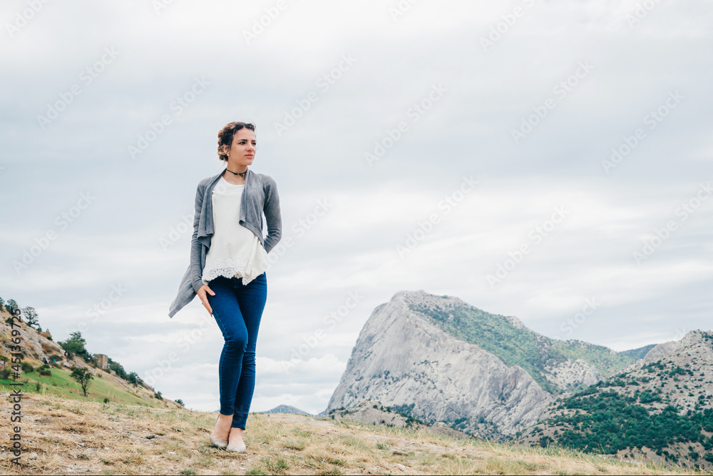 Caucasian girl traveler stands on the top of a mountain