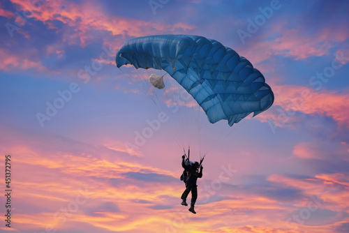 Silhouette of the Paramotor transportation control flying through soft sunlight sunset sky.