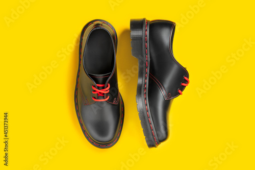 Stylish black leather shoes on yellow background, flat lay, top view