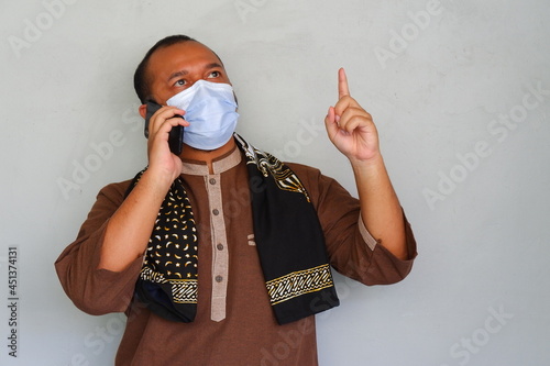 Muslim asian man wearing masker while make a phone call photo