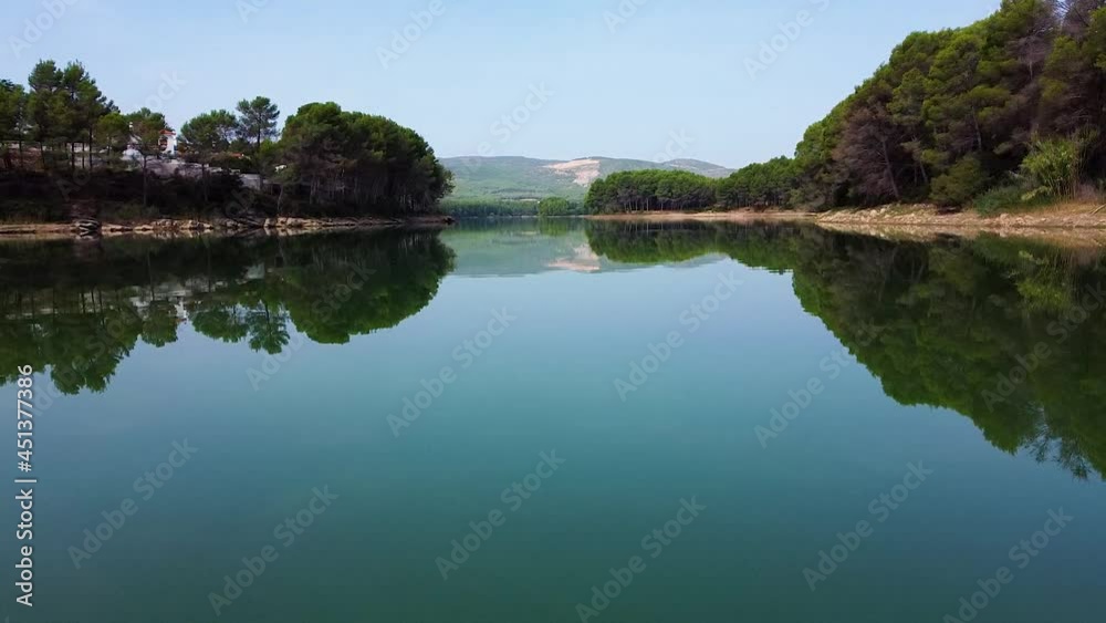 Drone slowly flying over a calm river, with amazingly clean water, surrounded by lush vegetation. Sky and Green bushes are reflecting on water. Drone slowly flying over a calm river, with amazingly clean water, surrounded by lush vegetation. Sky and Green bushes are reflecting on water.