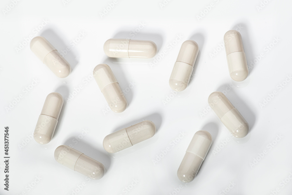 White capsules of medication on a white acrylic background White capsules of medication on a white acrylic background