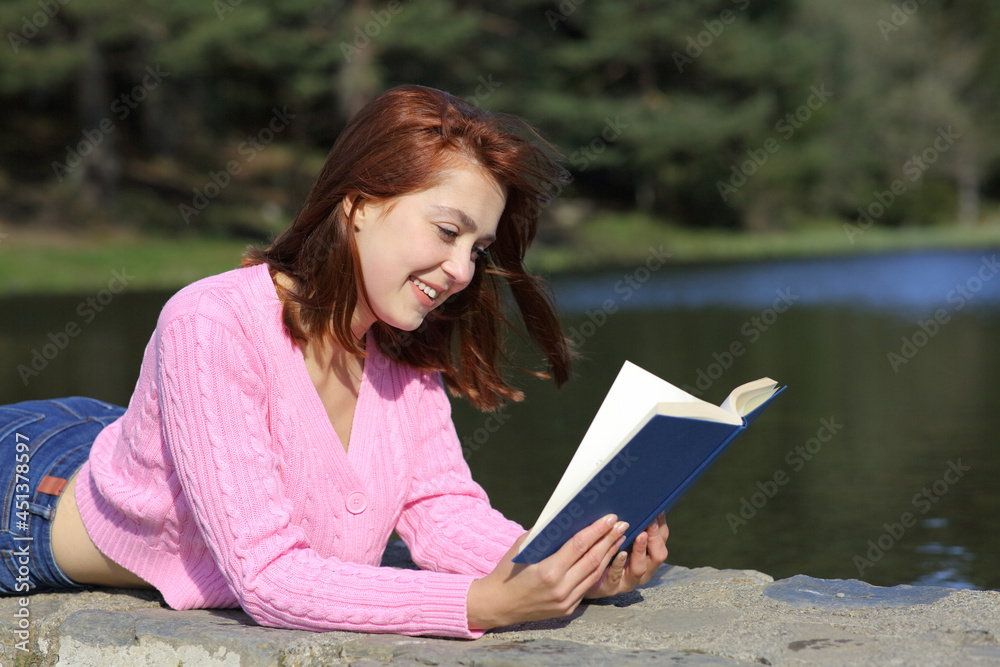 Obraz premium Woman reading a book lying in the mountain