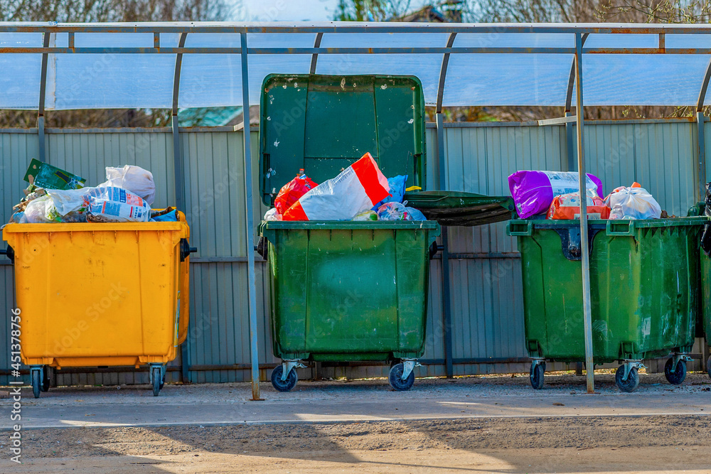 Overflowing dumpsters. A lot of garbage does not fit in large bins on wheels for collecting recyclables. Recycling and removal of waste. The concept of an environmentally friendly environment. Overflowing dumpsters. A lot of garbage does not fit in large bins on wheels for collecting recyclables. Recycling and removal of waste. The concept of an environmentally friendly environment.