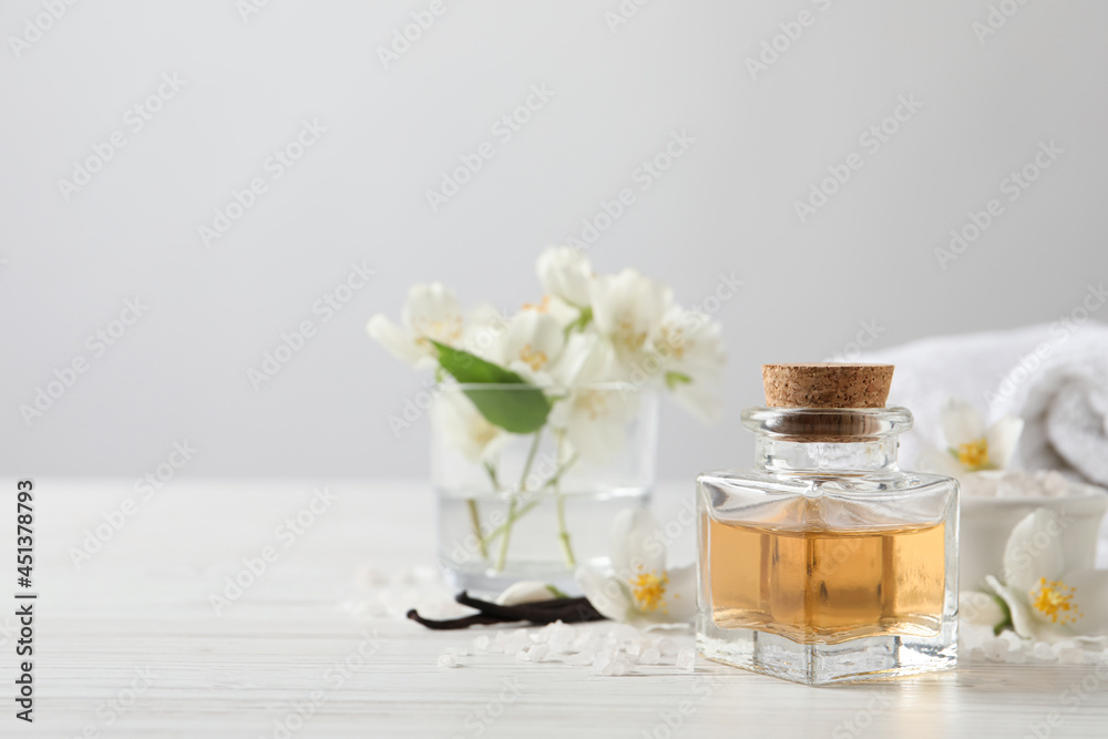 Beautiful composition with jasmine essential oil and fresh flowers on white wooden table. Space for text Beautiful composition with jasmine essential oil and fresh flowers on white wooden table. Space for text