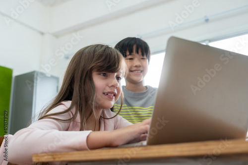 Diverse Multi ethnic of students girl and Asian boy enjoying using laptop for learning in classroom at primary school.