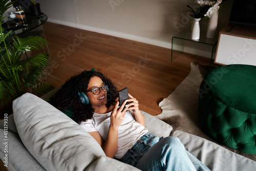 Bild auf Leinwand Mixed race female student working from home texting on cellular device listening