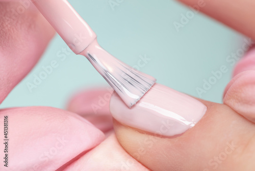 Close up process of applying pink varnish. Woman in salon receiving manicure by nail beautician. Pink Nail polish and brush, macro. photo