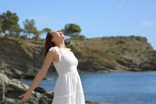 Woman in white screaming to the air on the beach on summer