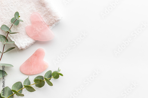 Rose quartz gua sha massage stone with green leaves photo