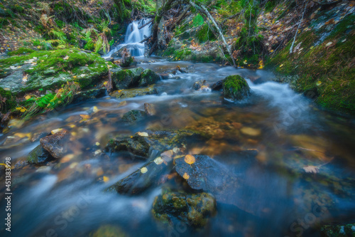 River waterfall landscape in autumn forest with orange and yellowish leaves of the trees at Guadarrama national park, Lozoya river, Spain
