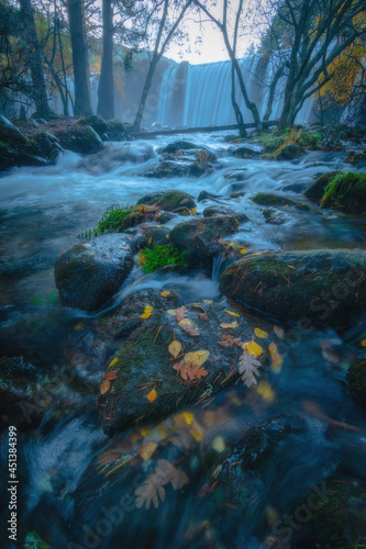 River waterfall landscape in autumn forest with orange and yellowish leaves of the trees at Guadarrama national park, Lozoya river, Spain
