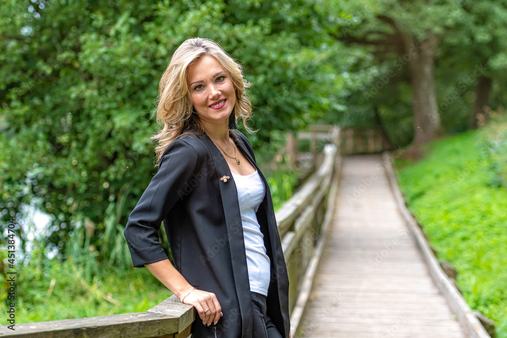 young blonde woman standing near wooden railings in park young blonde woman standing near wooden railings in park