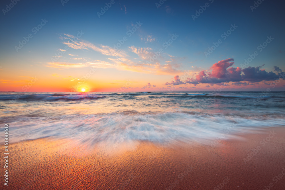 Colorful sunrise over tropical beach and sea with dramatic cloudscape