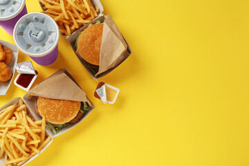 Different fast food on yellow background, flat lay. Space for text