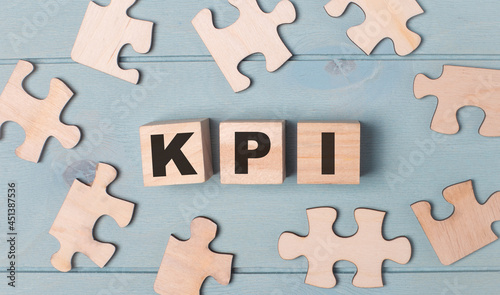 Blank puzzles and wooden cubes with the text KPI lie on a light blue background.