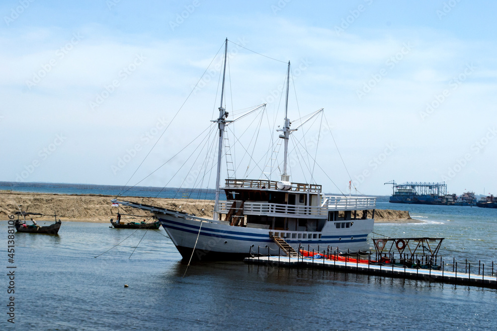 a large fishing boat is docked in the harbor with two boats in tow