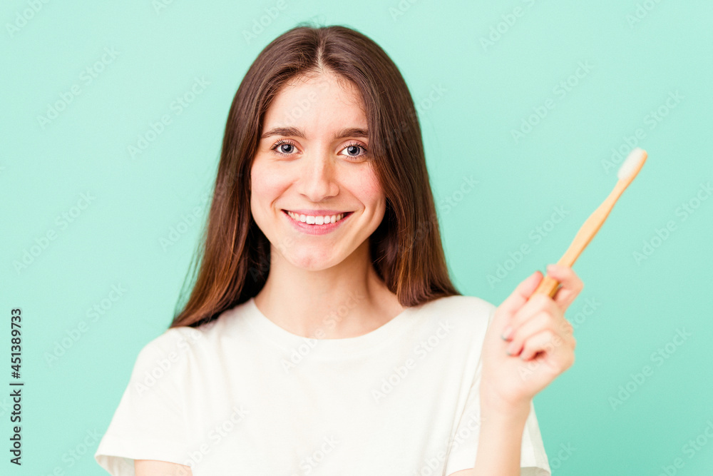 Young caucasian woman holding a toothbrush isolated on blue background
