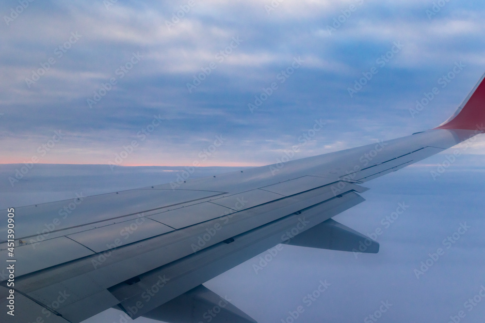 a view from a height above the clouds from the plane's window. part of an airplane wing in the frame