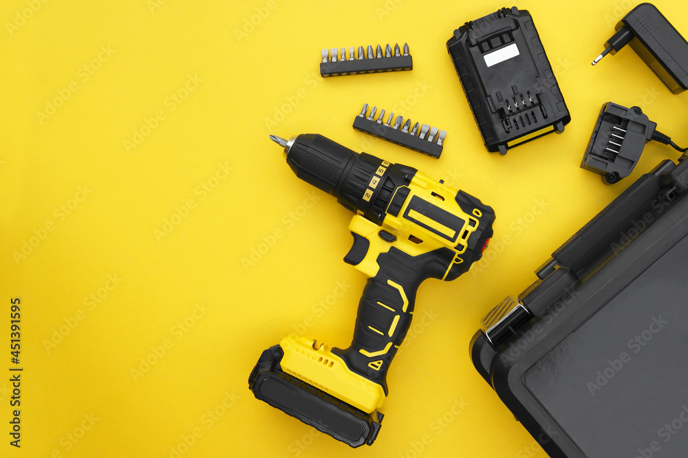 The yellow-black screwdriver on a yellow background, a set of bits. The yellow-black screwdriver on a yellow background, a set of bits.