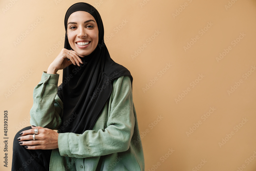 A smiling muslim woman in hijab posing and looking at the camera A smiling muslim woman in hijab posing and looking at the camera