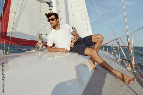 Young man drinking beer on his yacht in sea