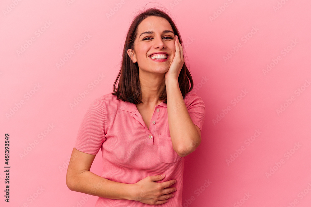 Young caucasian woman isolated on pink background laughs happily and has fun keeping hands on stomach. Young caucasian woman isolated on pink background laughs happily and has fun keeping hands on stomach.