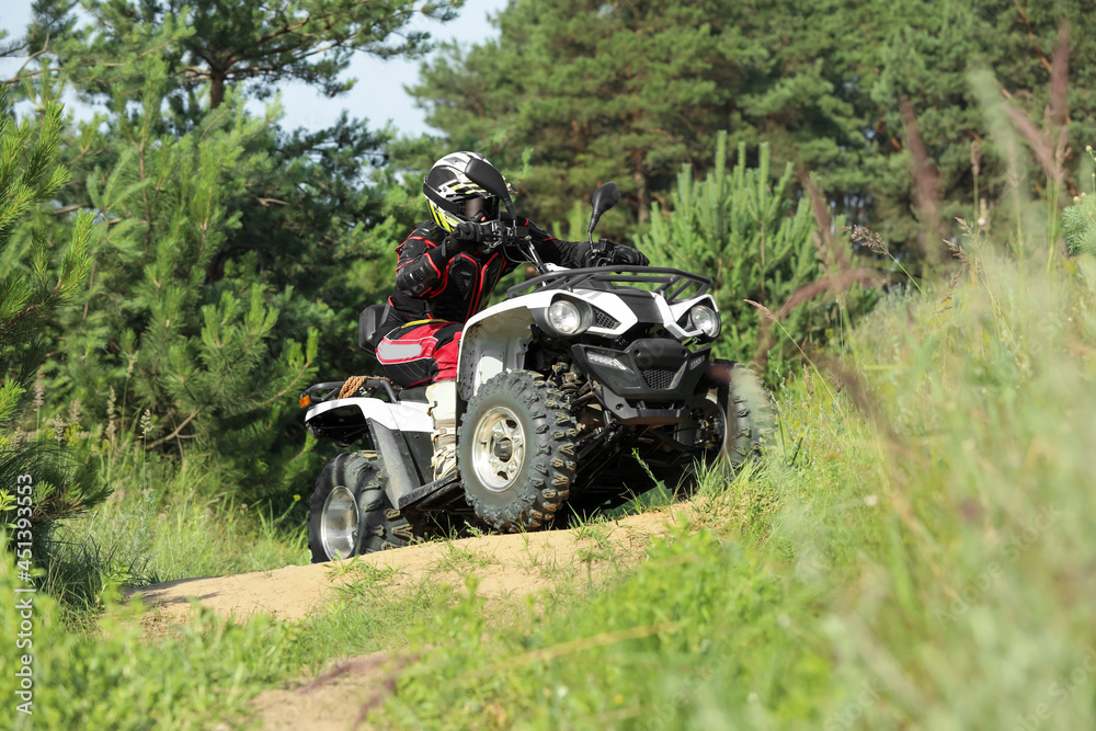 Man driving modern quad bike on sandy road near forest. Extreme sport Man driving modern quad bike on sandy road near forest. Extreme sport