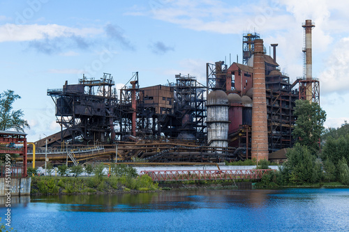 The building of the old factory on the river bank. Iron smelter against the blue sky.