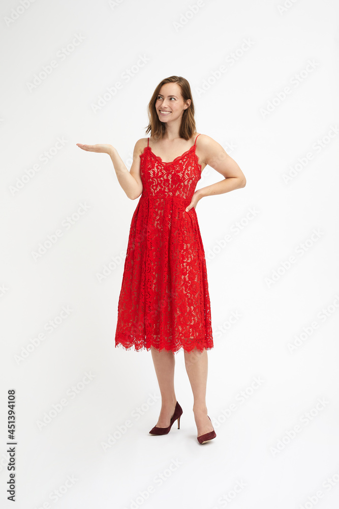 Full body portrait of a beautiful and glamorious woman in red dress showing a product on her palm looking at it Full body portrait of a beautiful and glamorious woman in red dress showing a product on her palm looking at it
