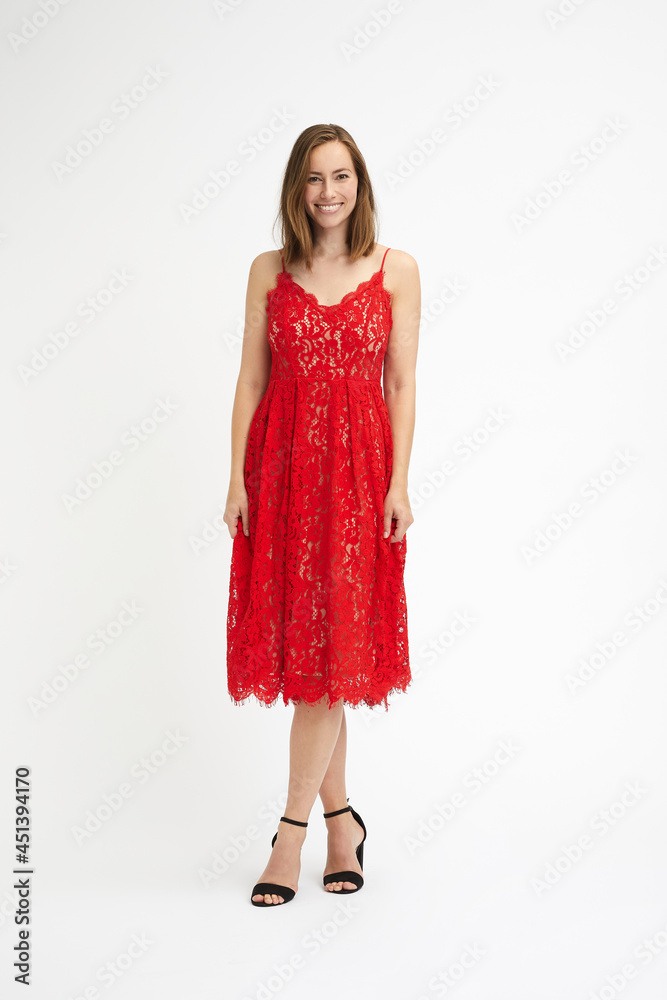 Full body portrait of a beautiful and elegant woman in a red party dress crossing her legs Full body portrait of a beautiful and elegant woman in a red party dress crossing her legs