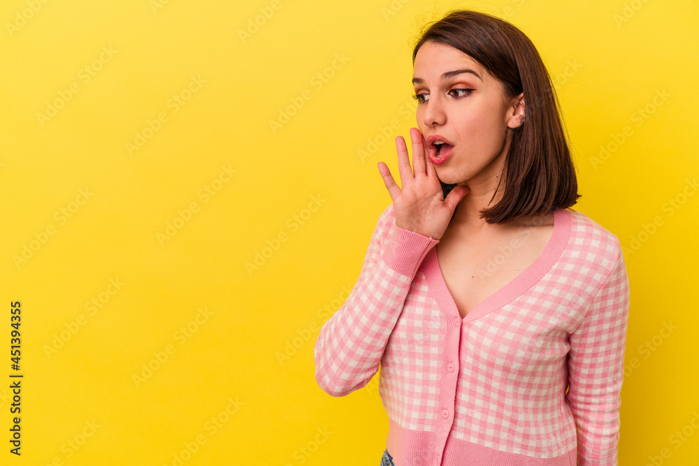 Young caucasian woman isolated on yellow background is saying a secret hot braking news and looking aside Young caucasian woman isolated on yellow background is saying a secret hot braking news and looking aside