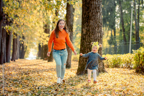 Smiling young family running into leaves on an autumns day.