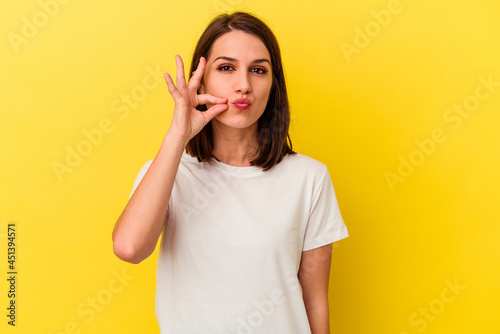 Young caucasian woman isolated on yellow background with fingers on lips keeping a secret.